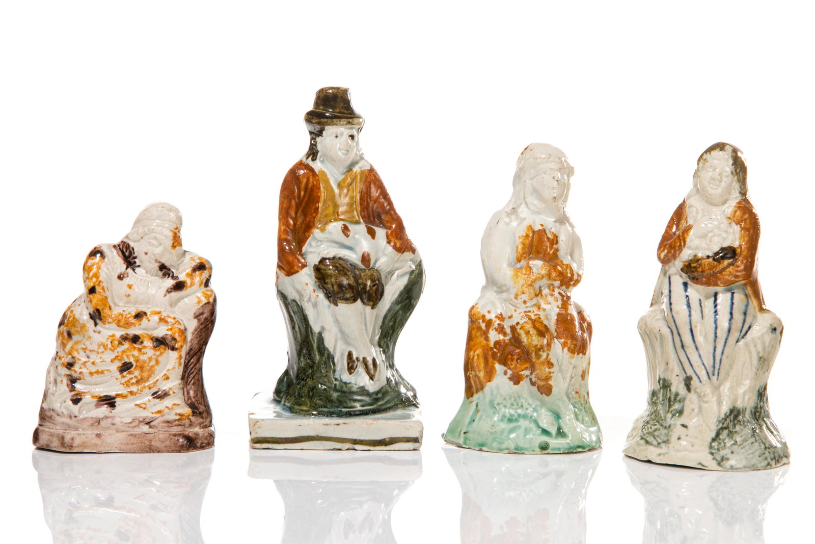 FOUR EARLY STAFFORDSHIRE PEARLWARE POTTERY FIGURES: Of figures holding fruit, a dog, reclining in brown and green mottled glaze, hollow undersides. H of tallest 11cm (4 1/4in)
