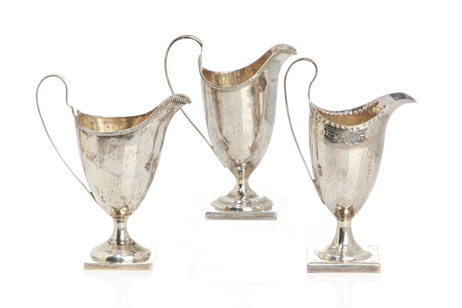 THREE GEORGE III SILVER HELMET JUGS, 280g: English, late 18th C. Comprising three jugs, two with beaded trims, each mounted on square pedestal bases. All London, with impressed makers marks Charles Hougham, 1792; George Gray, 1788 and the thir