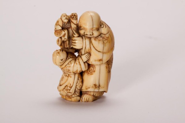 FINE JAPANESE NETSUKE BY HIDEMASA: Of a man holding a puppet with a child. Signed. 19th century. H 4.2 cm. (1 5/8 in.)