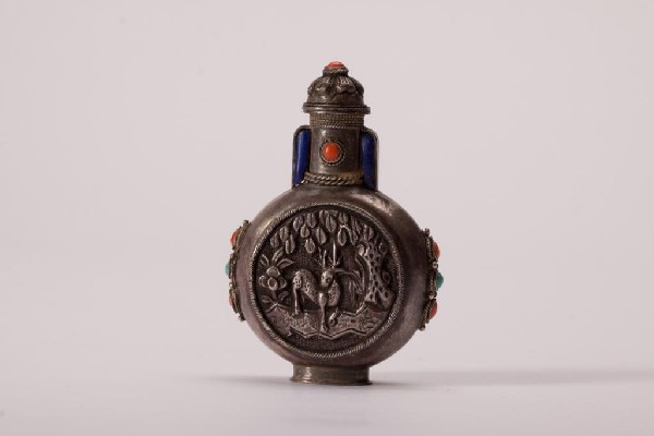 SINO MONGOLIAN SILVER JEWELLED SNUFF BOTTLE: Moon flask form with engraved circular panels of birds and an animal. Turquoise, lapis and coral jewelling. Unmarked. 19th century. H 8 cm (3 1/8 in.)