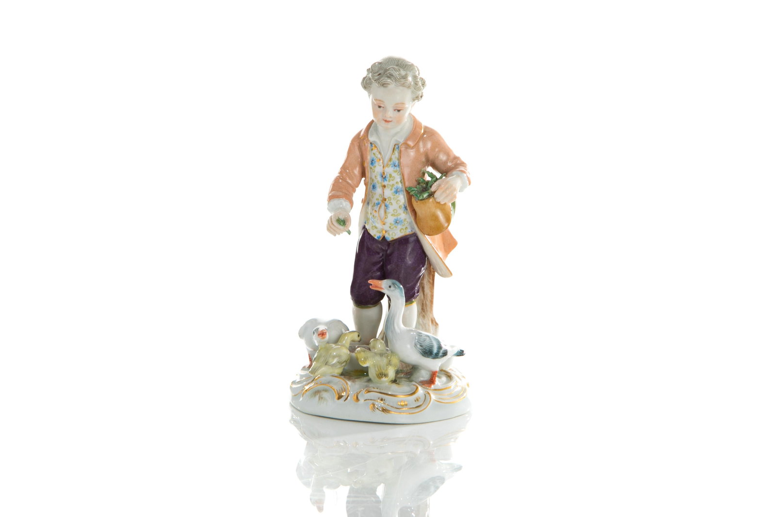 MEISSEN PORCELAIN FIGURE OF A BOY AND GEESE: A painted Meissen porcelain figure of a young boy feeding geese at his feet. Marked with crossed swords to base, first grade. H. 12.5cm (5in)
