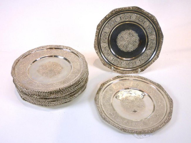 SET PERSIAN SILVER SMALL DISHES: Comprising 18 circular plates faceted with 10 sides each. Applied floral border with floral engraved decoration. Each marked, Iranian, mid 20th century. D 17.2 cm. Total weight 3953 grams.