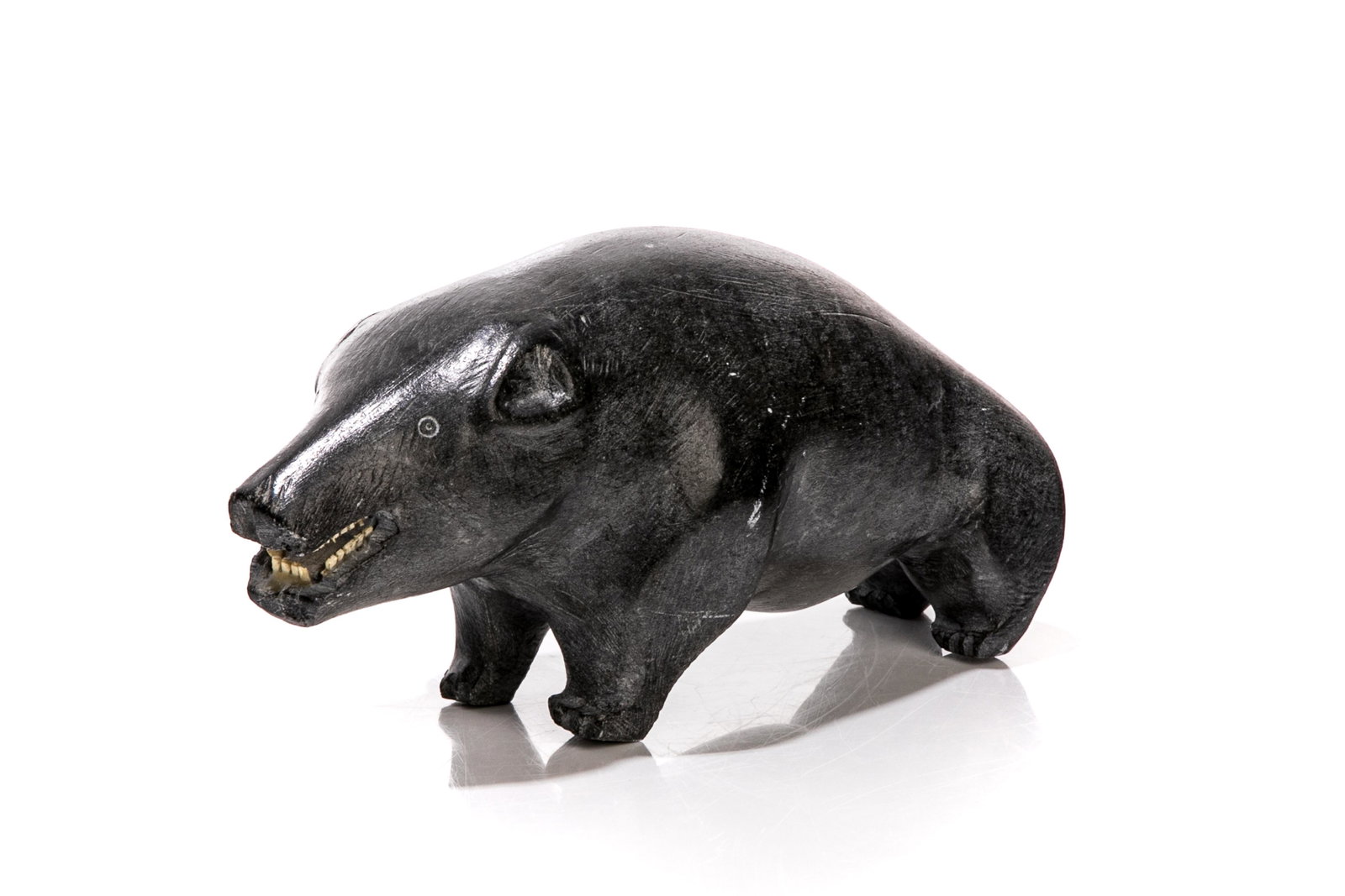 INUIT SOAPSTONE STANDING BEAR: Standing bear with natural exposed teeth. Disc number E9-639 and syllabic signature. L. 26.5 cm (10 1/2 in.) Bidders living outside of Canada are warned to proceed with care before bidding on this lot