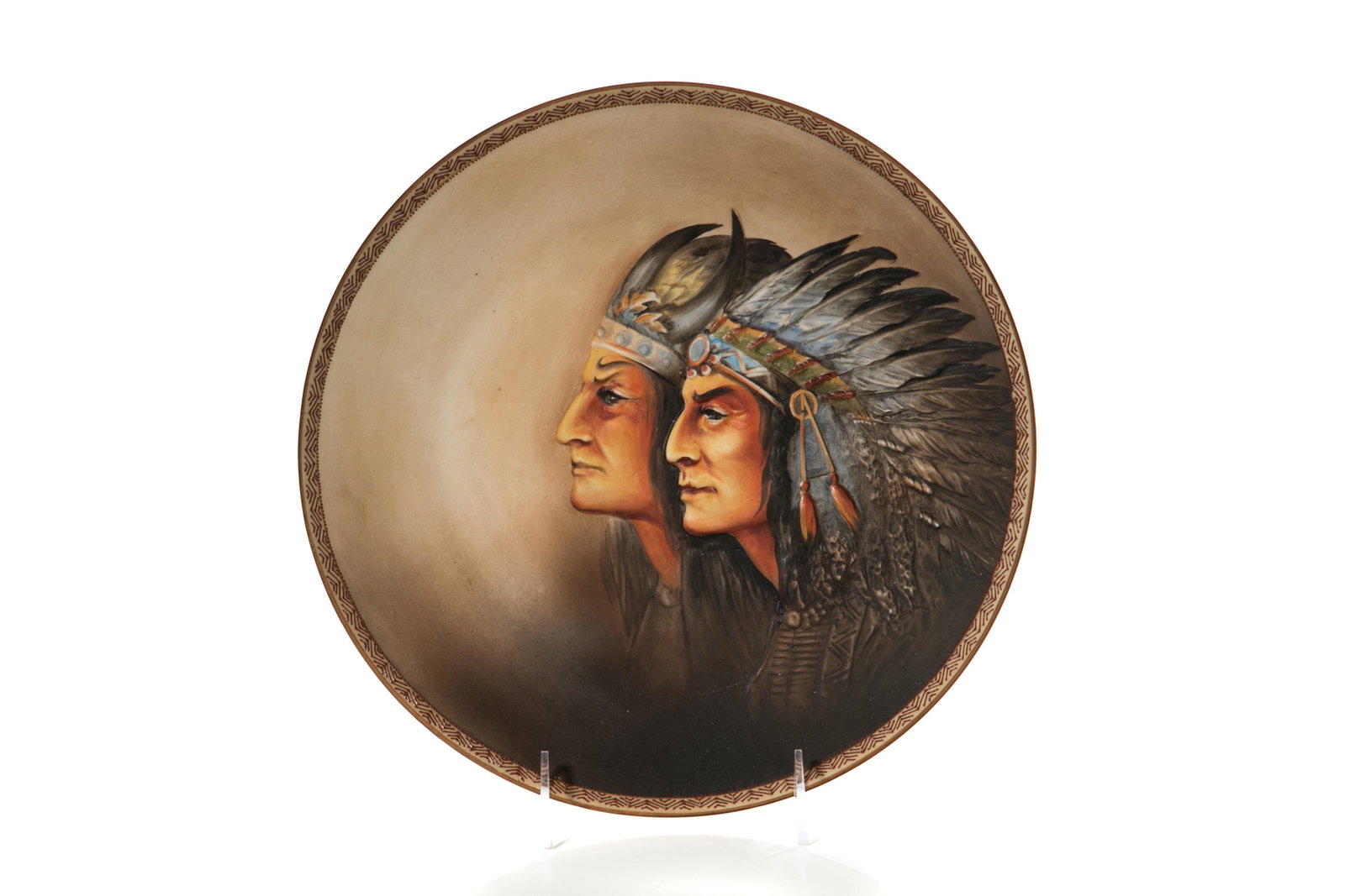 AMERICAN INDIAN NIPPON PORCELAIN WALL PLAQUE: Mold blown, hand-painted Nippon porcelain wall plaque of two American Indians wearing headpieces in relief, smoky brown background, geometric patterned moriage edge. Japanese, green M inwreath, early 