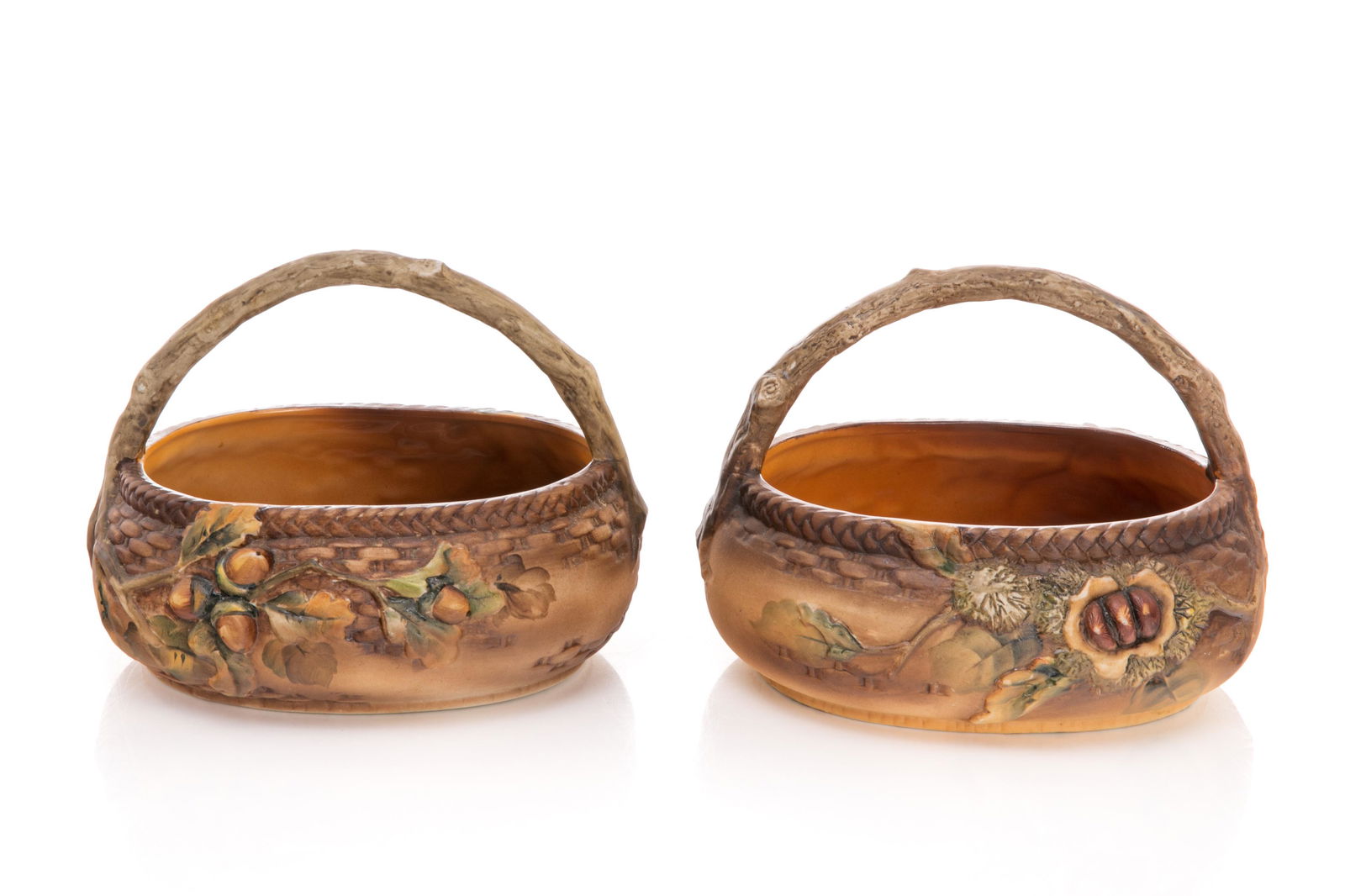 TWO NIPPON MOLD BLOWN BASKET BOWLS: Brown glazed matte ground with mold blown nuts, basket weave detail, and branch handle. Japanese, green M in wreath mark, early Noritake. H. of tallest: 14 cm (5 1/2 in.)