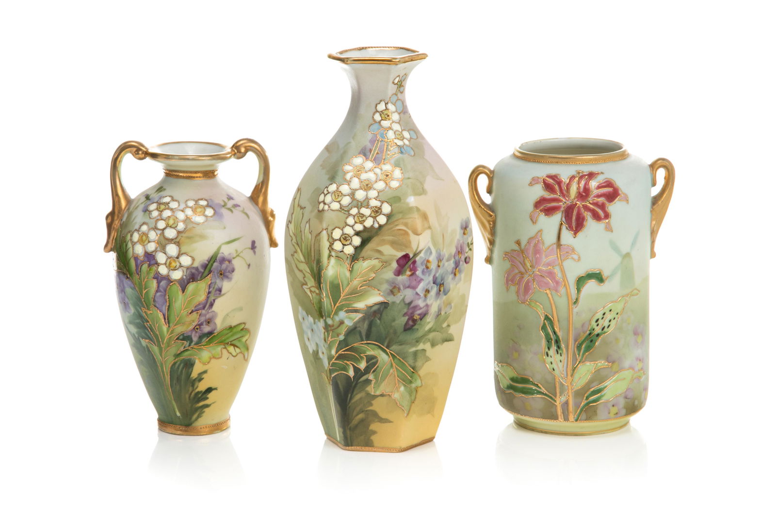 THREE PIECES OF NIPPON PORCELAIN: Two matching matte glaze vases with hand painted flowers and gilded decoration. Together with a two handled gilded vase with pink lilies. Japanese, green M in wreath mark, early Noritake. H. of talles