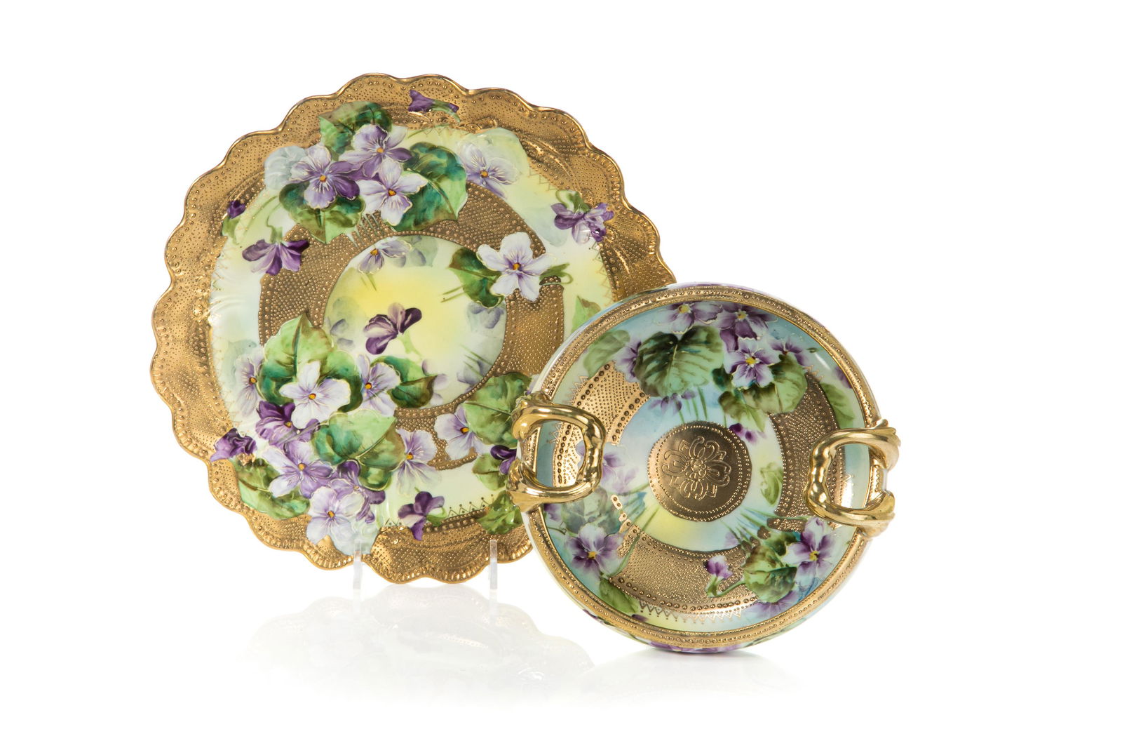 NIPPON PORCELAIN PLATE & BOWL: Scalloped edge plate in high gloss finish with hand painted violets and gilded decoration. Together with a matching two handled bowl. Japanese, green maple leaf mark, early Noritake. Dia. of plate: 25