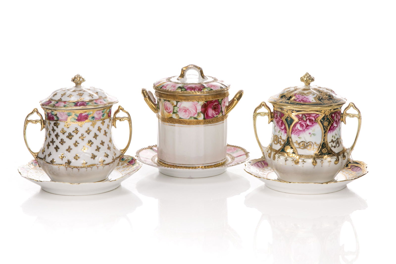 THREE NIPPON PORCELAIN CONDENSED MILK SETS: Three hand painted Nippon porcelain condensed milk containers with rose and gold decoration. One container marked RC Noritake Nippon, together with two containers with Japanese, blue maple leafmarks,
