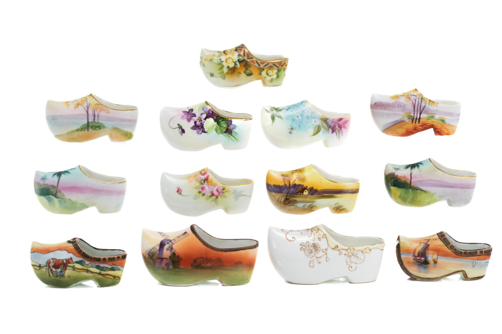 THIRTEEN NIPPON PORCELAIN MINIATURE CLOGS: Various hand painted scenes and flowers, both matte and high gloss finishes, some featuring moriage and gilded decoration. Japanese, green M in wreath mark, early Noritake.