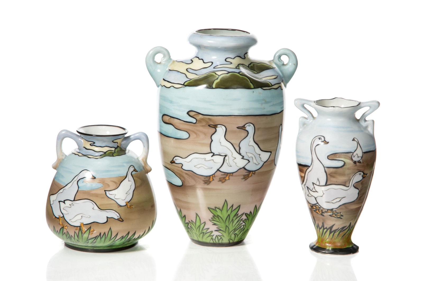 THREE NIPPON TWO HANDLED DUCK VASES: Blue ground with hand-painted white ducks and beach scene, black painted base and rim. Japanese, blue maple leaf mark, early Noritake. H. of tallest: 20 cm (8 in.)