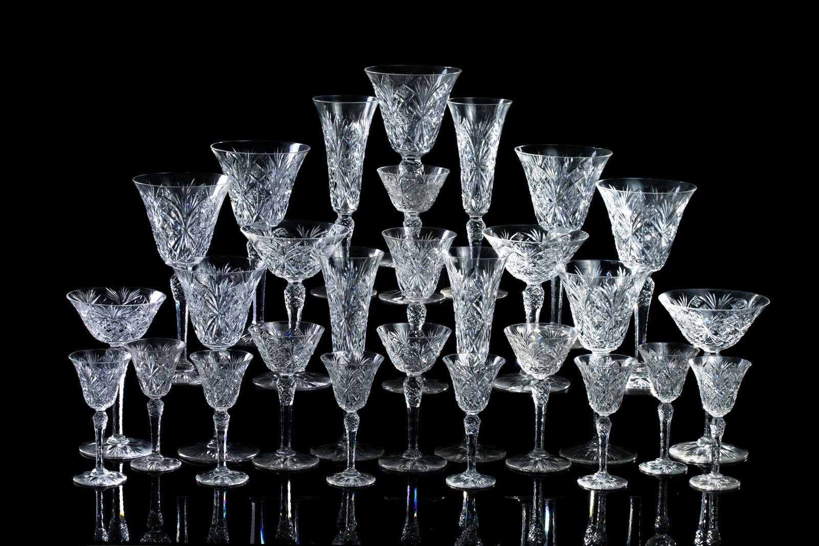 27 MUSSETTE BY ST LOUIS CUT GLASS STEMWARE: Twenty seven Mussette by St. Louis pattern glasses featuring crisscross and fan cuts, and cut stem and foot. Including four champagne flutes, five water goblets, two wine glasses, four martiniglasses,