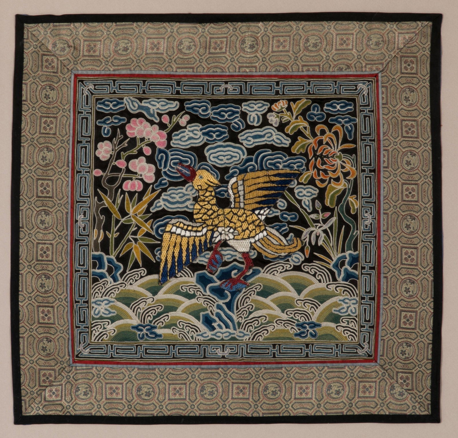 FRAMED CHINESE RANK BADGE WITH BIRD: Chinese, 20th century, a civilian back rank badge featuring a bird with red beak and feet (probably 7th rank Duck) applied to background embroidered in chain stitch having pink peonies and orange chry