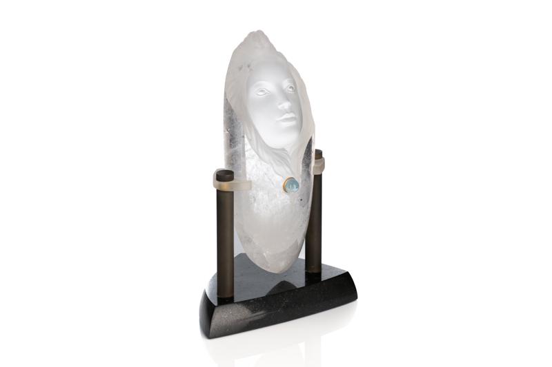 ROCK CRYSTAL SCULPTURE IN THE STYLE OF F. HART: A small rock crystal carved and polished with the face of a woman, a small inlaid aquamarine cabochon to centre. In the style of American artist Frederick Hart. With custom plinth of black onyx, obscu