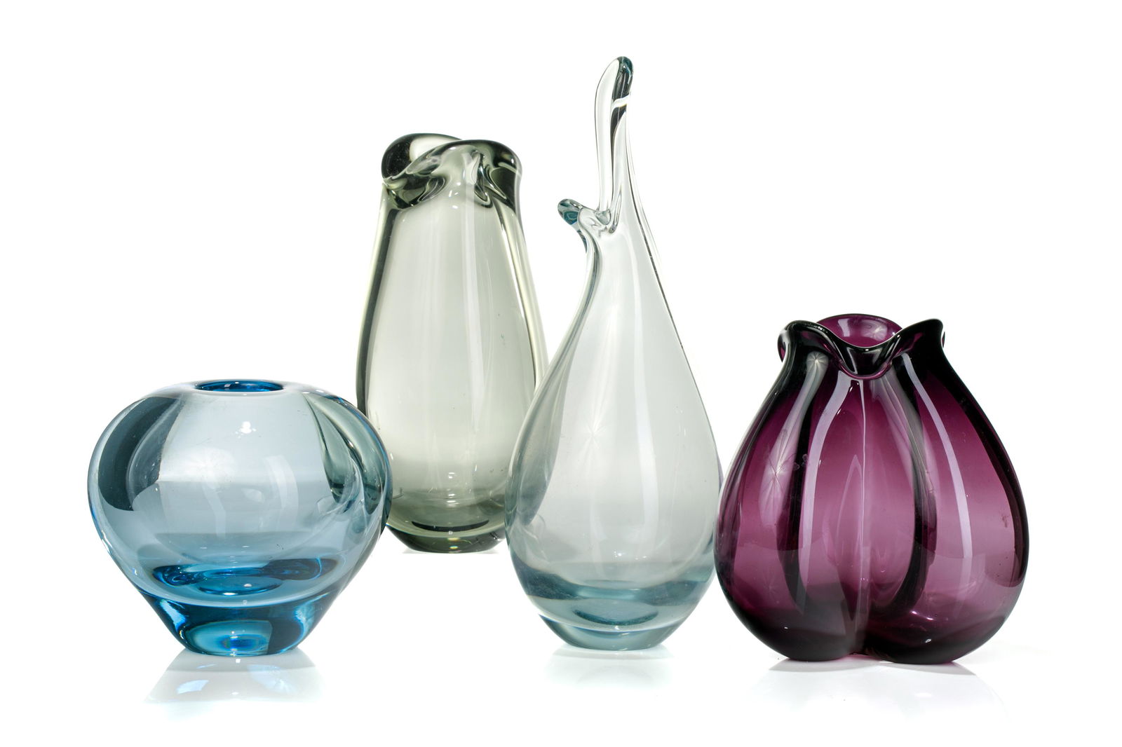 FOUR PER LUTKEN FOR HOLMEGAARD GLASS VASES: Four vessels of various oblong shape, of purple, smoky quartz, aquamarine and clear blown glass. All etched to base Holmegaard, mid 20th C. H. of tallest vase: 25cm (9 7/8in)
