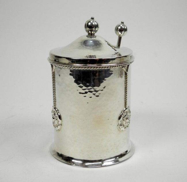 ENGLISH ARTS & CRAFTS SILVER CONDIMENT CANISTER: A.E. Jones, Birmingham, 1910. Cylindrical hand hammered form embellished with applied rope twist and stylized Tudor roses. Together with matching spoon. Ht. 12.5 cm. (5in.) 163 grams