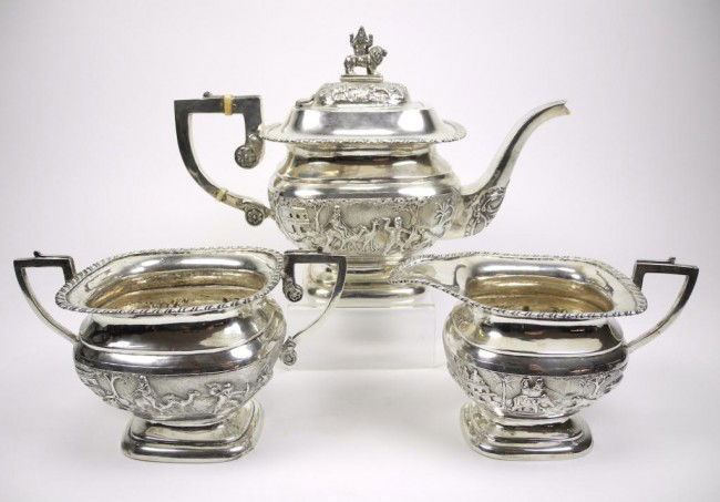 INDIAN COLONIAL SILVER THREE PIECE TEA SET: English form decorated in chased and repoussed panels depicting a tiger and other hunting scenes. The tea pot finial depicts Durga riding on a lion. 28cm. (11 in.) 1432 grams