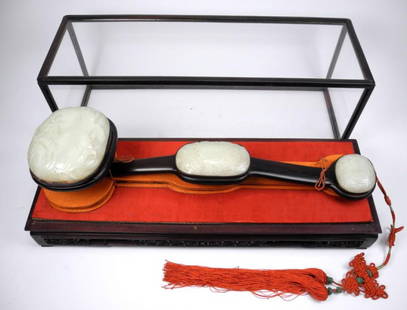 FINE CHINESE WHITE JADE RUYI SCEPTER: Made of Zitan wood with three white jade plaques. The largest finely carved with peaches and the others with fruit also. Mounted on a stand with the original glass case and wood storage box. China, 19