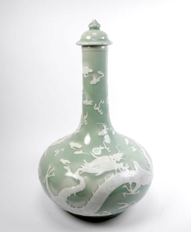 CHINESE CELADON BOTTLE VASE WITH DRAGON: Squat body with slender neck and lid. Decorated with a white glazed dragon among clouds, fire, etc. China, 19th century. H 40 cm (15 3/4")