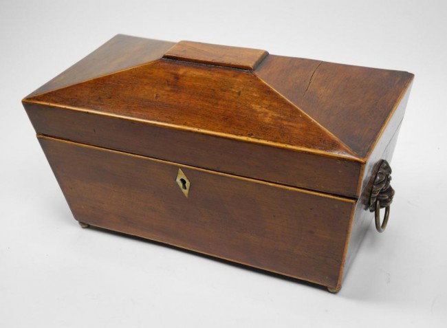 GEORGIAN TEA CADDY: English 19th century A mahogany tea caddy with two tin lined compartments and a recess for the mixing bowl. Brass lion mask handles on four brass ball feet. 29.5 cm. (115/8 in.)