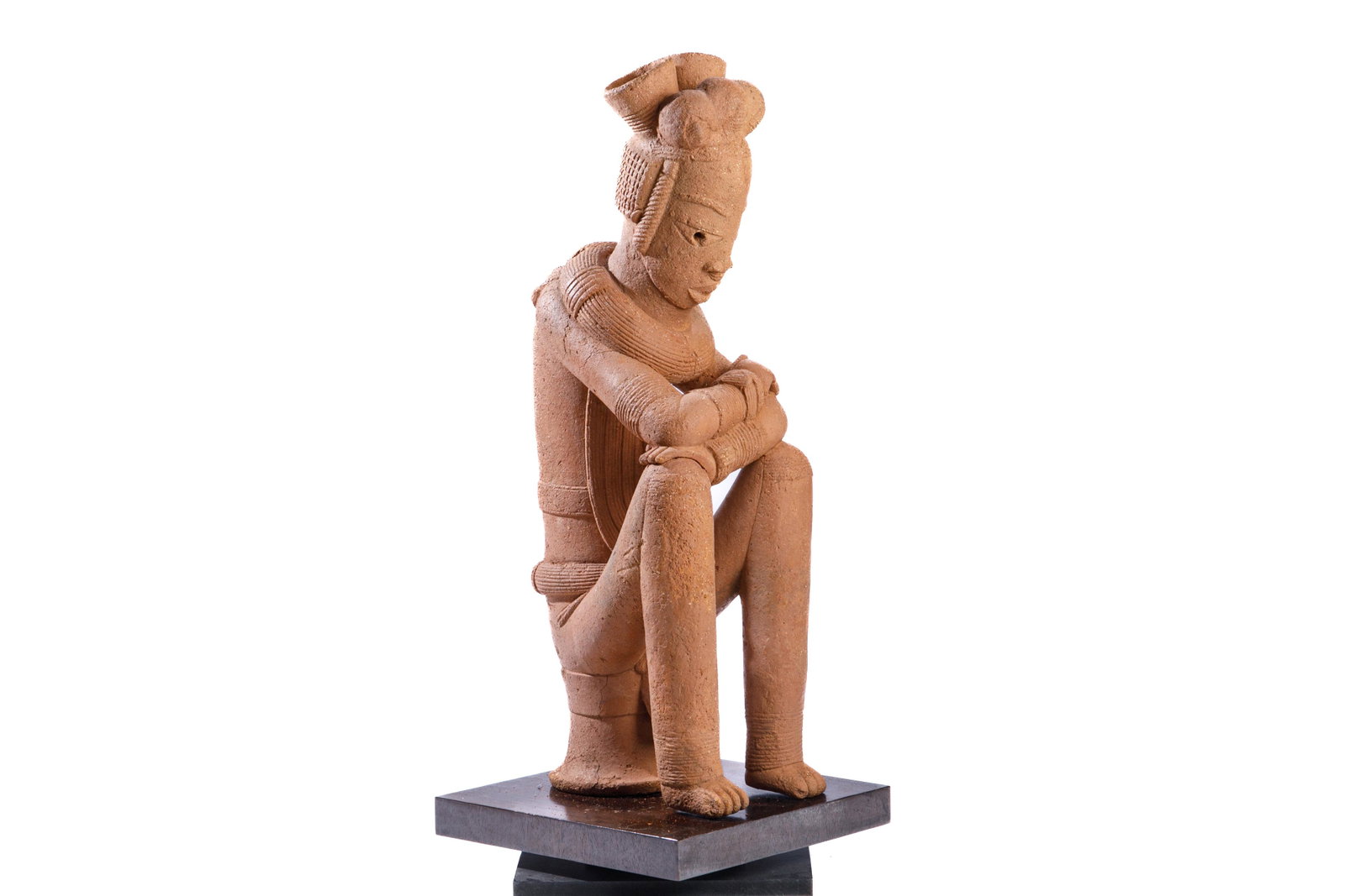 DECORATIVE NOK NIGERIAN TERRACOTTA FIGURE: West Africa, Nigeria, Nok culture. Exact dates unknown, fired clay / terracotta pottery. A stylized nude male seated figure with carved striated garments. Figure has crossed arms resting on his knees,