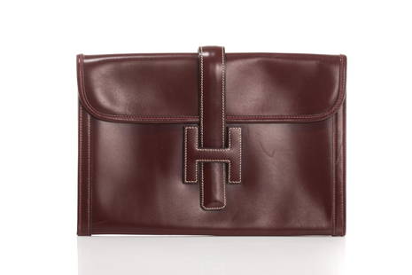 VINTAGE HERMES BURGUNDY LEATHER JIGE ENVELOPE BAG: Burgundy leather with cream coloured stitching, strap closure with H detail, canvas lined interior. W. 29cm (11 1/2 in.) L. 19.4cm (7 3/4 in.)