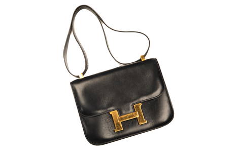 EARLY HERMES INDIGO LEATHER CONSTANCE BAG: The clutch in indigo lambskin blue leather with a gold metal H closure and shoulder strap. Stamped in gold Hermes Paris, Made in France. W 8 1/2 in.