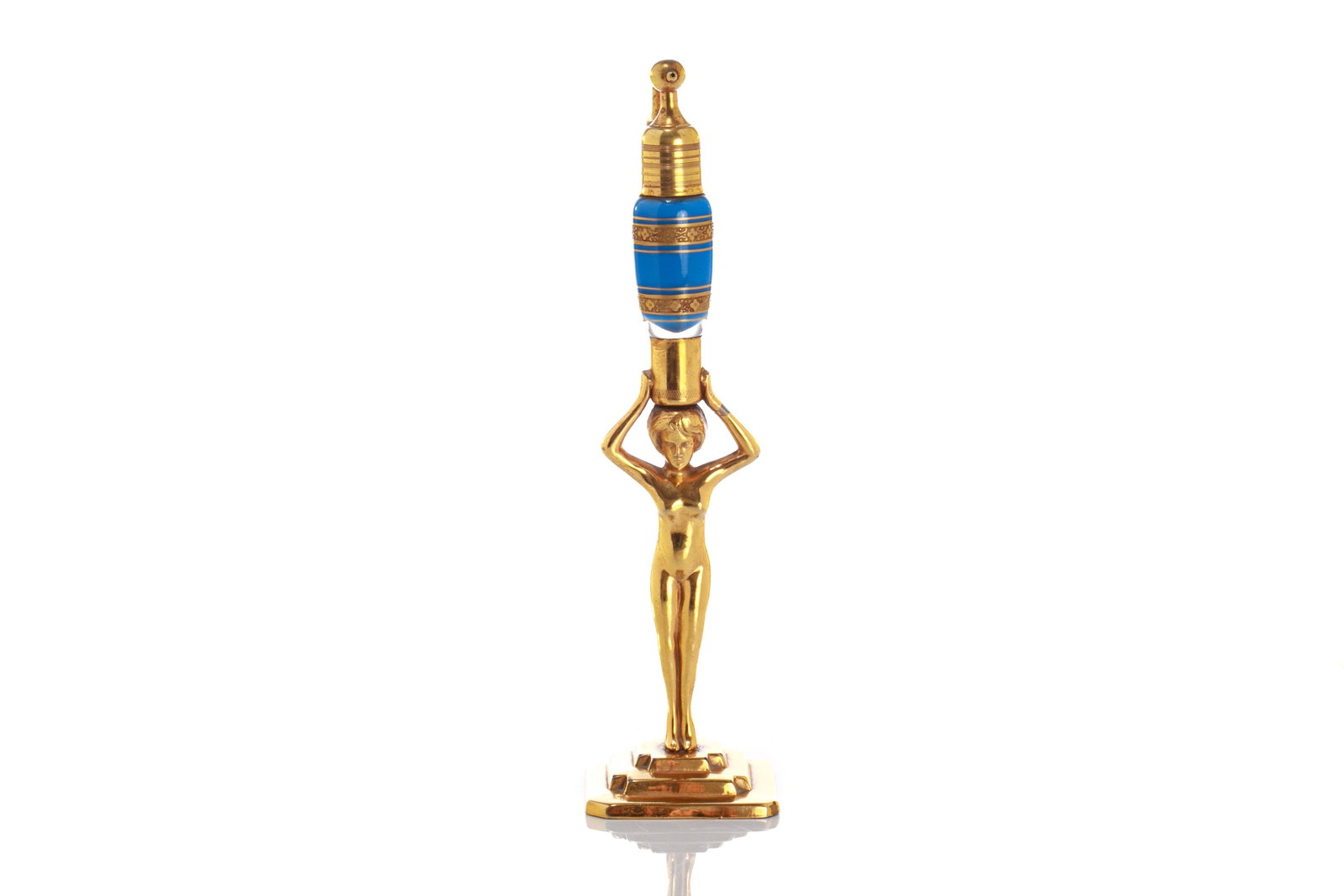 ART DECO VOLUPTE FIGURAL ATOMIZER: With a nude female holding up a coloured glass perfume bottle and extended metal atomizer. Original paper label and patent pending marks to base. H. 23.5 (9 1/4 in.)