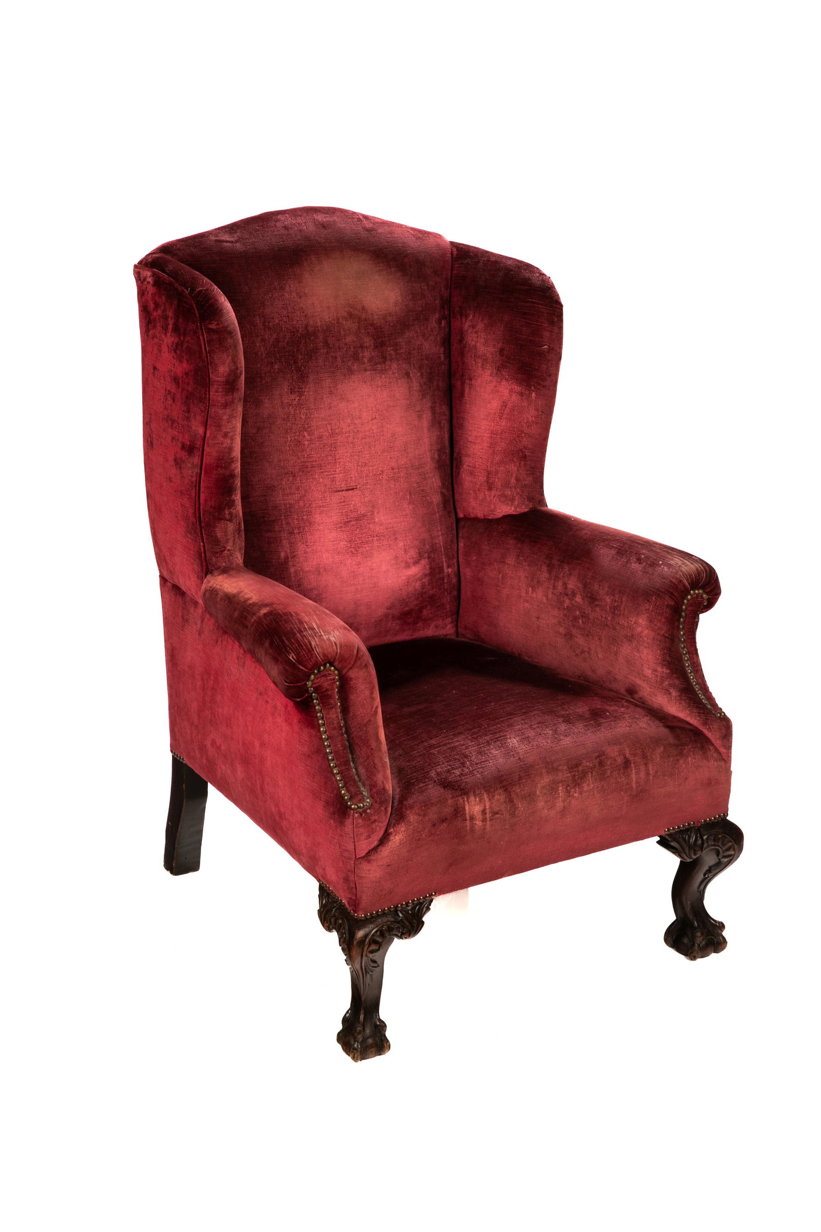 EDWARDIAN ENGLISH UPHOLSTERED WINGBACK ARMCHAIR: Heavily carved wood frame on ball and claw feet with period burgundy upholstery. English, early 20th C.H. 44 1/4" W. 32" D. 32"