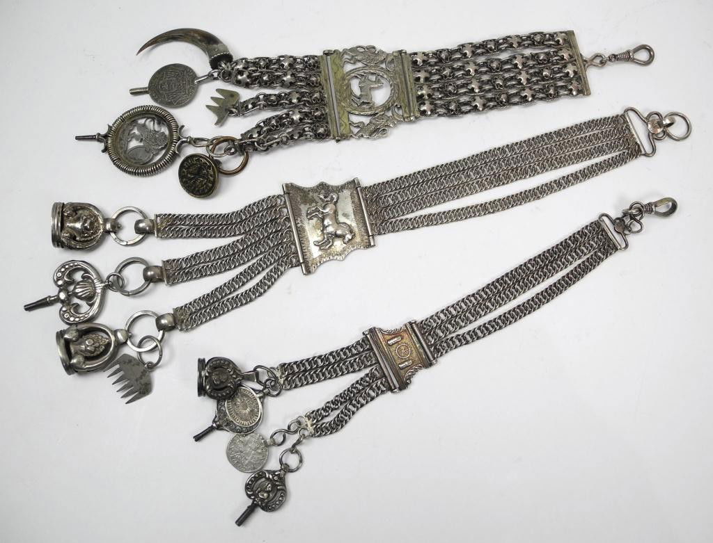 THREE SILVER CHATELAINES WITH FOBS: European or Near Eastern origin. Each chatelaine is hung with multiple fobs and pocket watch keys. One marked with a 12 lothige mark another marked 13. weight 241 gm. Length 27 cm.