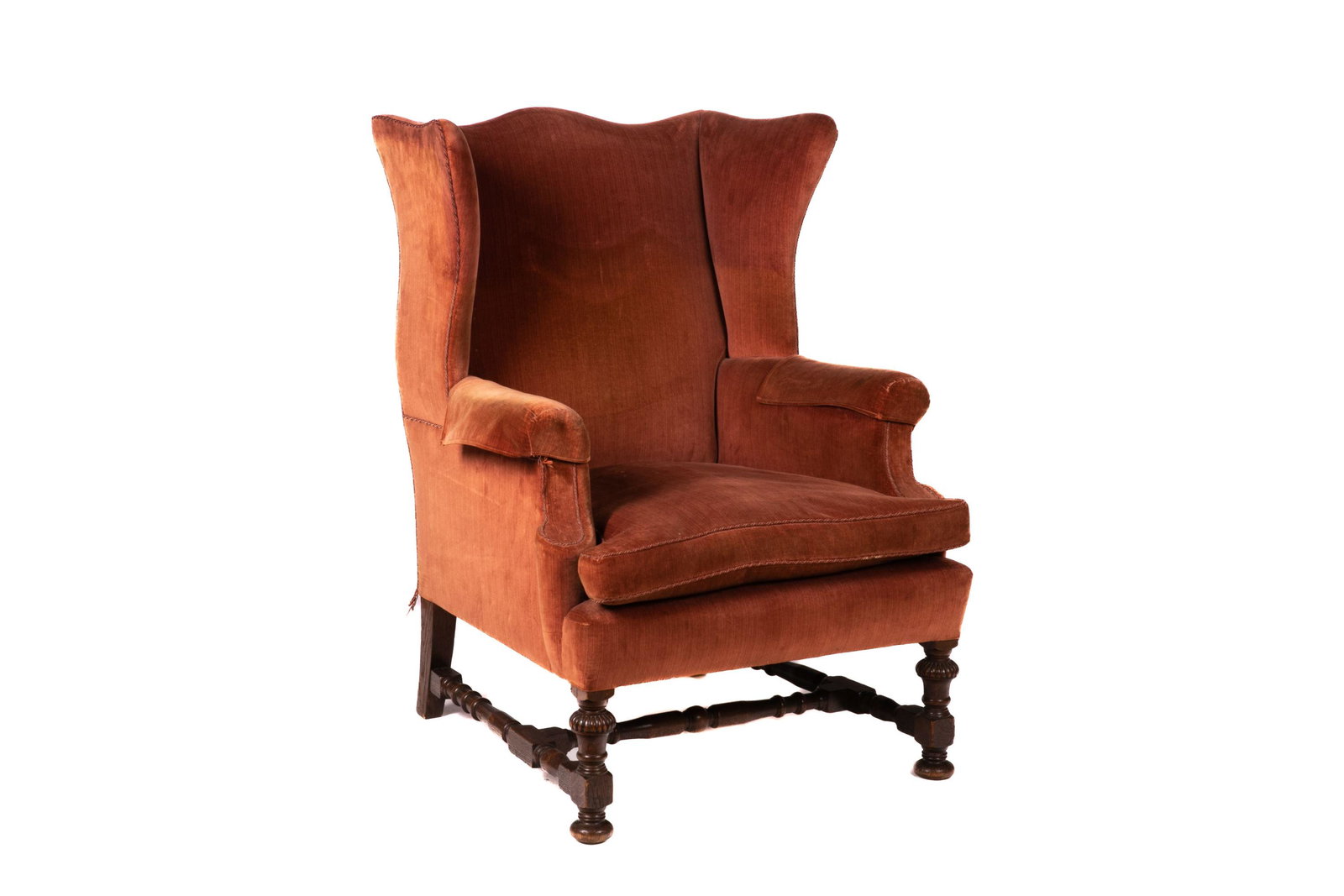 LATE 19th C GEORGIAN STYLE WINGBACK ARMCHAIR: A burnt orange upholstered wingback armchair in the manner of a Georgian example set upon carved wood frame with H stretcher. English, late 19th C. H. 41 W. 30 1/2 D. 33