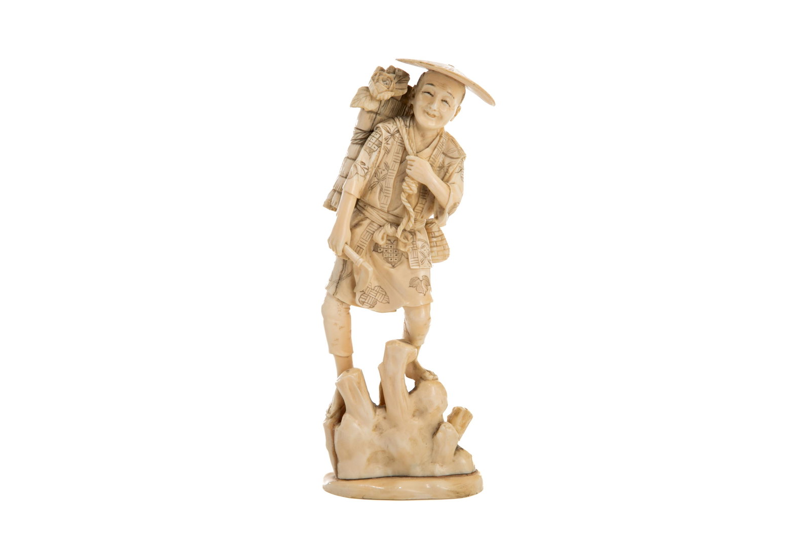 JAPANESE NATURAL CARVED OKIMONO OF A MAN: Japanese, carved as a smiling logger carrying a basket of wood with one hand and holding a forest axe on the other, standing on felled trees.H. 20.7 cm (8 1/8 cm)