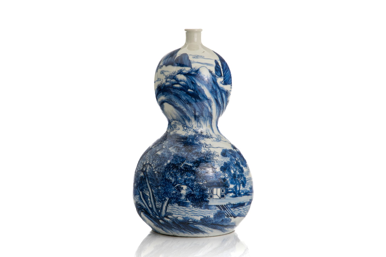A JAPANESE BLUE & WHITE DOUBLE GOURD VASE: Japanese, of double gourd form, finely painted with landscape in blue and white, with unglazed base.H. 43.2 cm (17 in.) Having a sprayed restoration from the mouth rim to the neck.