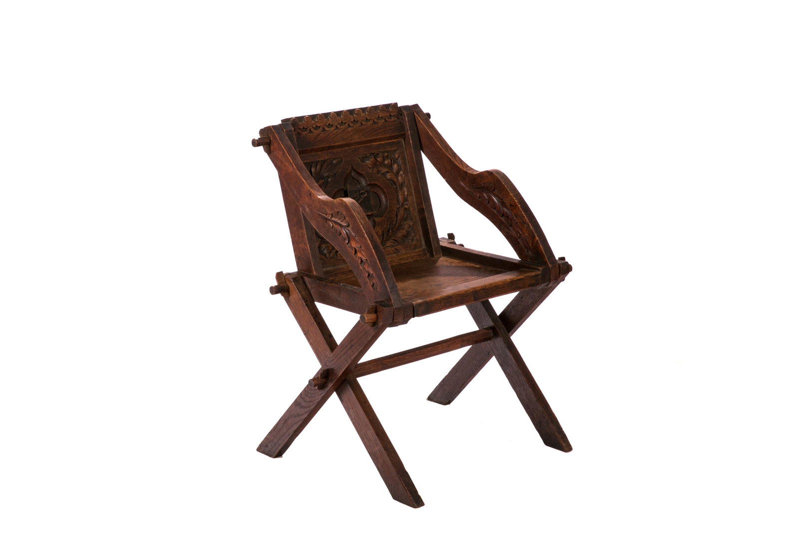 VICTORIAN GLASTONBURY CARVED WOOD CHAIR: A Victorian copy of the Glastonbury chair. The oak chair made with typical mortice and tenon construction. The back carved with a stylized fleur de Lis motif and a central shield incorporating a famil
