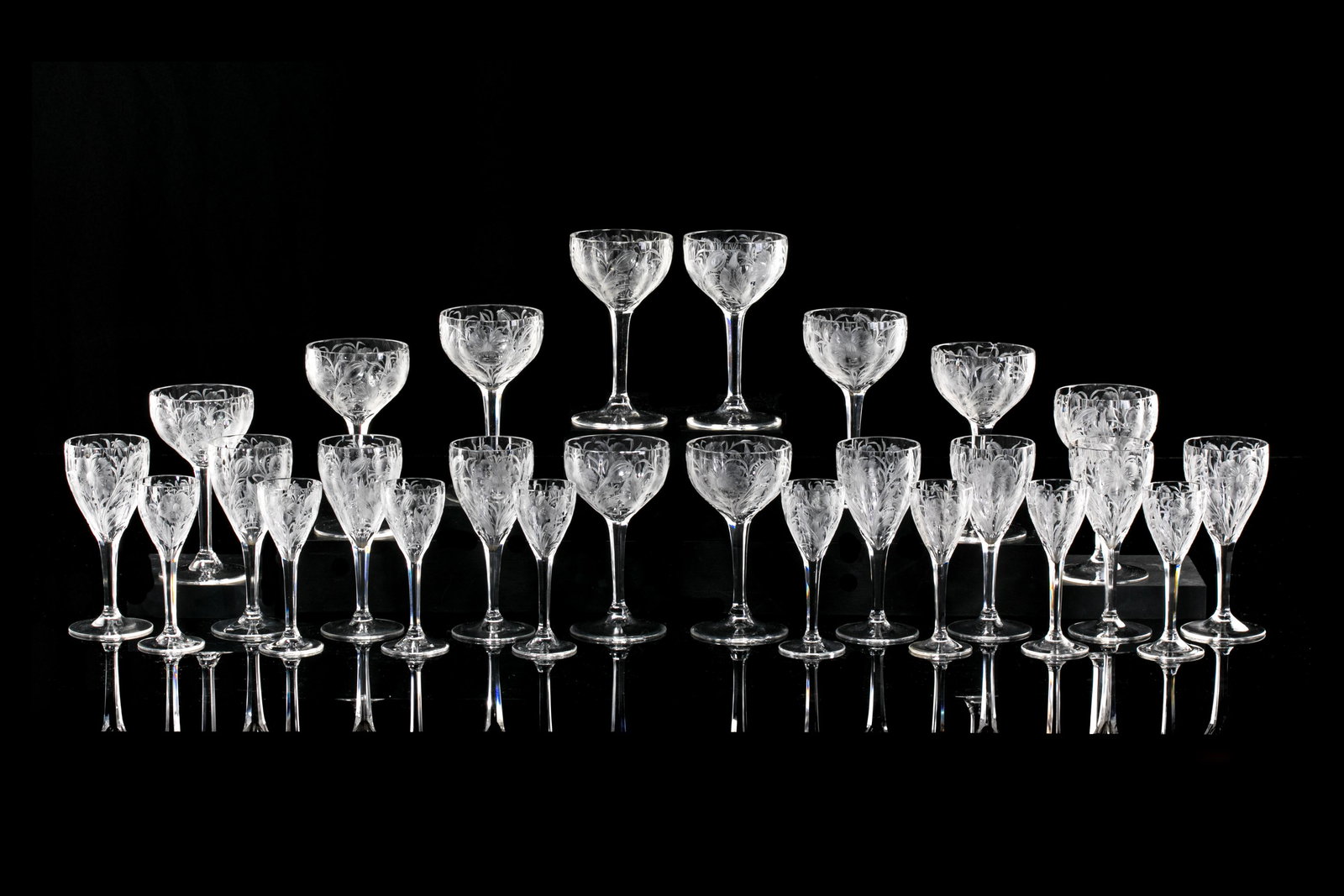 TWENTY-SIX BOHEMIAN ACID ETCHED LIQUEUR GLASSES: A grouping of twenty-six liqueur glasses of acid etched floral pattern and fluted form. Comprising ten port wine stems, eight sherry glasses, and eight cordial glasses. Attributed to Moser, circa1920s