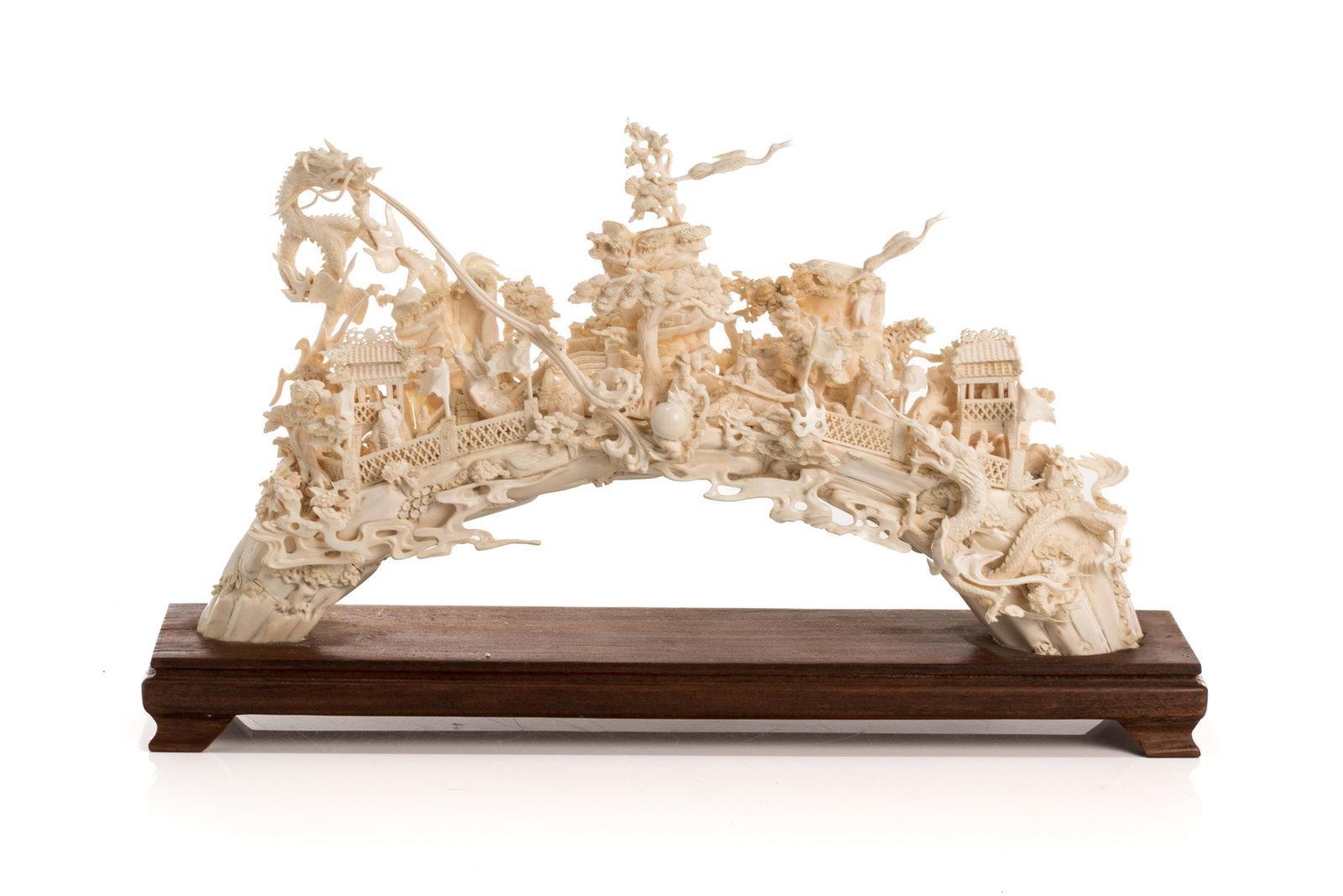 CHINESE NATURAL CARVED BRIDGE WITH WOOD STAND: Chinese, 20th century, finely carved of a bridge with figures, pavilions, trees, and dragons, on a custom wooden stand, with pieces of fragments. H. of carving: 20.3 cm (8 in.), L. of carving: 36.2 cm