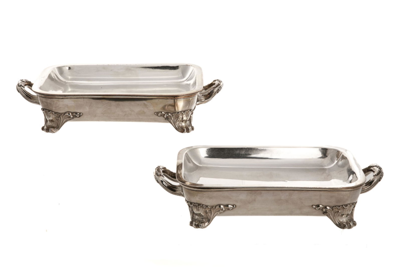 PAIR OF SHEFFIELD PLATE WARMING STANDS: Two English Sheffield plate tureen bases, each with two applied handles and raised on four scrolling feet. Hallmarked to the underside for Roberts, Smith & Co., 1828. L. handle to handle: 36.5 cm (14