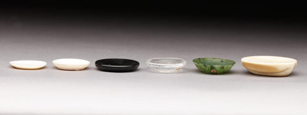 SIX SNUFF PLATES OF IVORY, JADE, WOOD & GLASS: Includes a larger ivory snuff plate with carved base, and a dark green jade plate with brown veins. D. 2.9 -4.2 cm (1.1-1.7 in.)