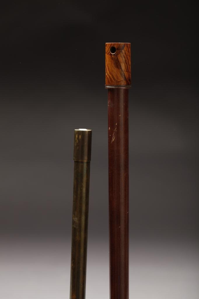 TWO BATON & PIPE SYSTEM CANES: Includes a wooden straight handle cane that transforms into a pipe stem and bowl, and an inscribed mother of pearl baton stick inside a brass container with inserted American dollar coin. L. 86.5cm (3