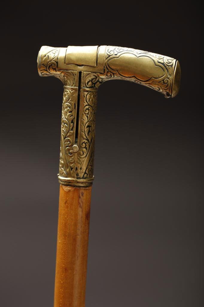 19TH CENTURY BRASS HANDLED SYSTEM CANE: Interior of cane houses an adjustable pushup candle, cap opens to store matches. L. 91.5cm (36 in.). Similar example is featured in Jeffrey B. Snyder's 2004 book "Cane and Walking sticks: a stroll thr