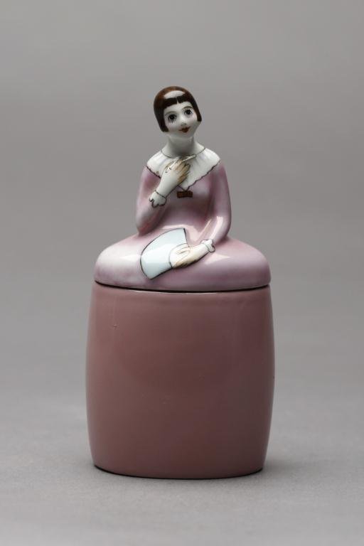 NORITAKE FIGURAL DRESSER JAR: Girl in a pink dress holding a fan and cigarette. Green M-in-Wreath, H 14.6 cm. (5 3/4 in.)