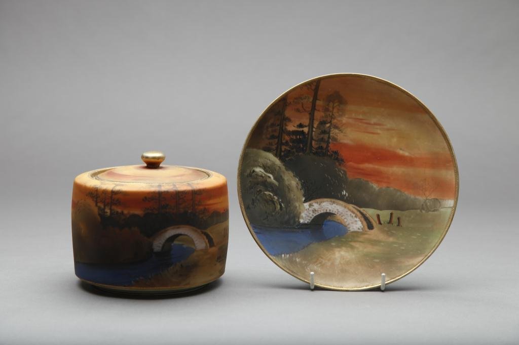 NIPPON HAND PAINTED HUMIDOR AND PLAQUE: Both with a bridge and stream with orange sunset. Green M-in-Wreath, Dia of plaque 21.6 cm. (8 1/2 in.) Minor wear to paint