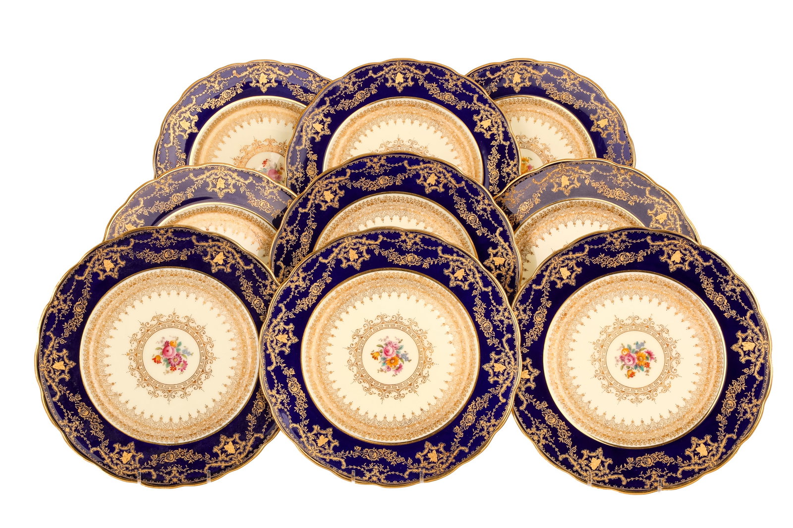 TWELVE ENGLISH PORCELAIN SERVICE PLATES: Each with cobalt blue rim and gilded floral and swag motifs. The centre with painted floral bouquet surrounded by gilded decoration. Marked to underside Crescent, George Jones & Sons. Dia. 26 cm (10 1