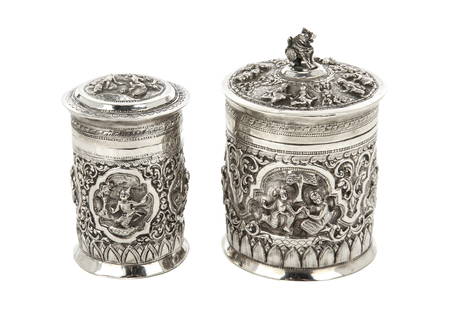 TWO BURMESE SILVER TEA CADDIES: 19th-20th century silver molded tea caddy, decorated with protruding relieves on the exterior surface, with the recurring devotional ritual scenes. H. bigger one: 13 cm (5 1/8 in.); smaller one: