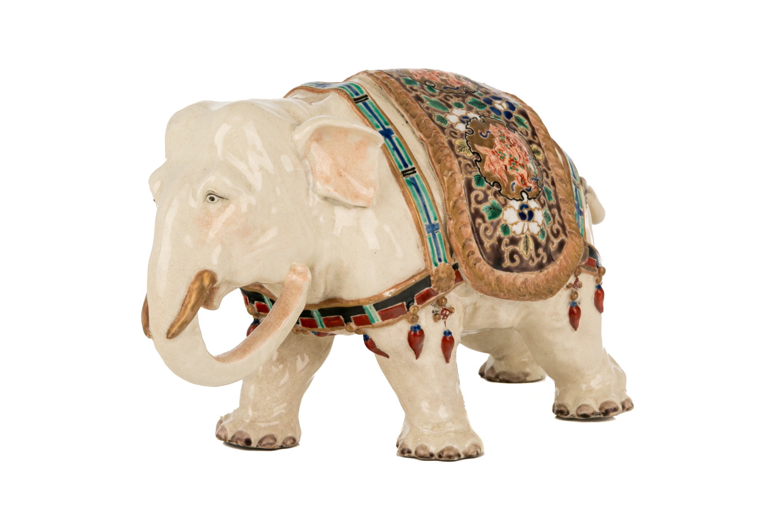 JAPANESE SATSUMA POTTERY ELEPHANT: The white pottery moulded elephant wearing dress and blanket with enamel flowers, 19th C Meiji period. H 18.5cm (7 1/4in)