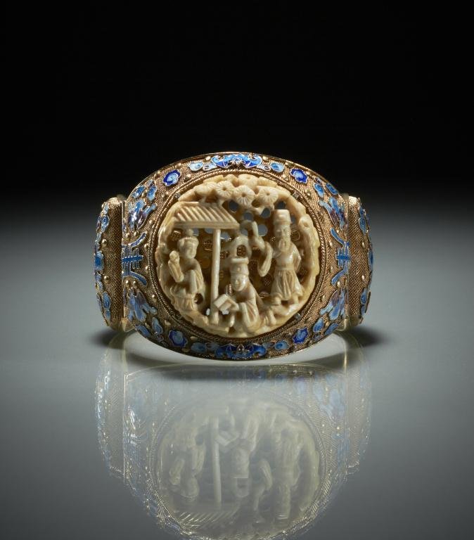 CHINESE SILVER FILIGREE AND ENAMEL BANGLE BRACELE: Chinese vermeil with blue to purple enamel bats, flowers and fortune symbols, with a finely carved ivory pendant. W. 8.5cm (3 3/8 in.)/ width of the ivory pendant 4.5cm (1 3/4 in.) Provenance: from th