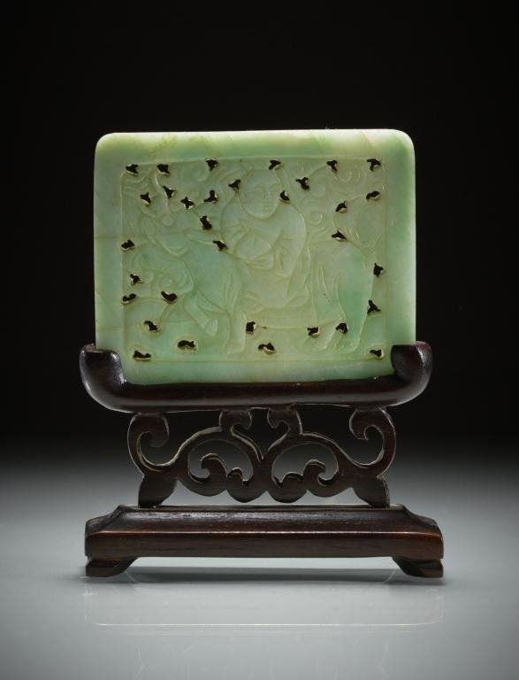 CHINESE CARVED JADE PLAQUE: Pale celadon and apple green jade. Rectangular carving in low relief with a man riding a qilong on fitted carved wood stand. W. 5.4cm (2 1/7 in.) Provenance: from the collection of Mr. Abraham Abraham