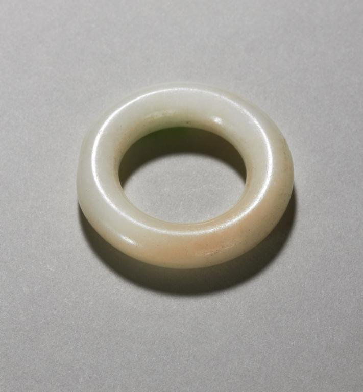 CHINESE WHITE JADE RING: With a small patch of apple green jade. Dia 3.5 cm. (1 3/8 in.) Provenance: from the collection of Mr. Abraham Abraham of The Jade Shop, Toronto.
