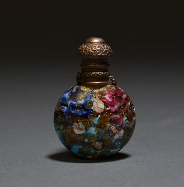 VENETIAN MURRINI PERFUME BOTTLE: Decorated with various faces using the murrini cane technique. The round bottle has brass mounts and a chatelaine attachment, 19th century. 6 cm (2 3/8 in.)