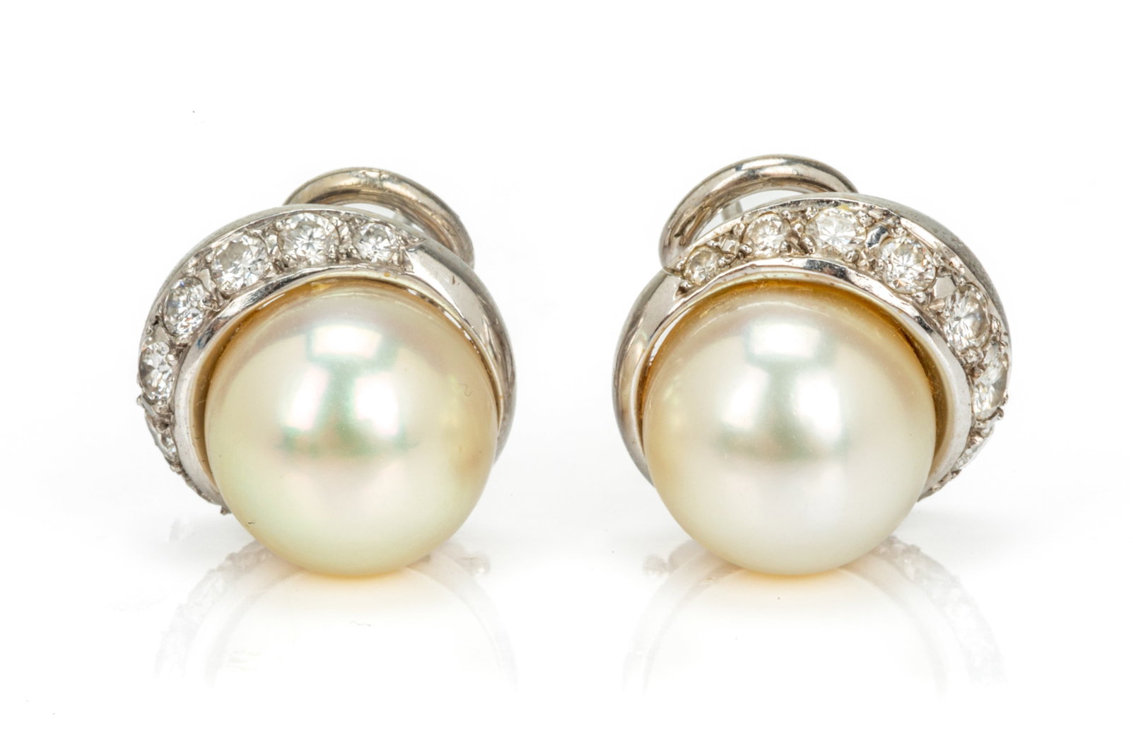 PAIR OF 14K WHITE GOLD AND PEARL EARRINGS, 9g: A pair of Beni Sung 14k white gold earrings, each earring set with a cultured pearl and a row of tapered diamonds, marked Beni 14k, with omega clip backings. L. 1.4cm