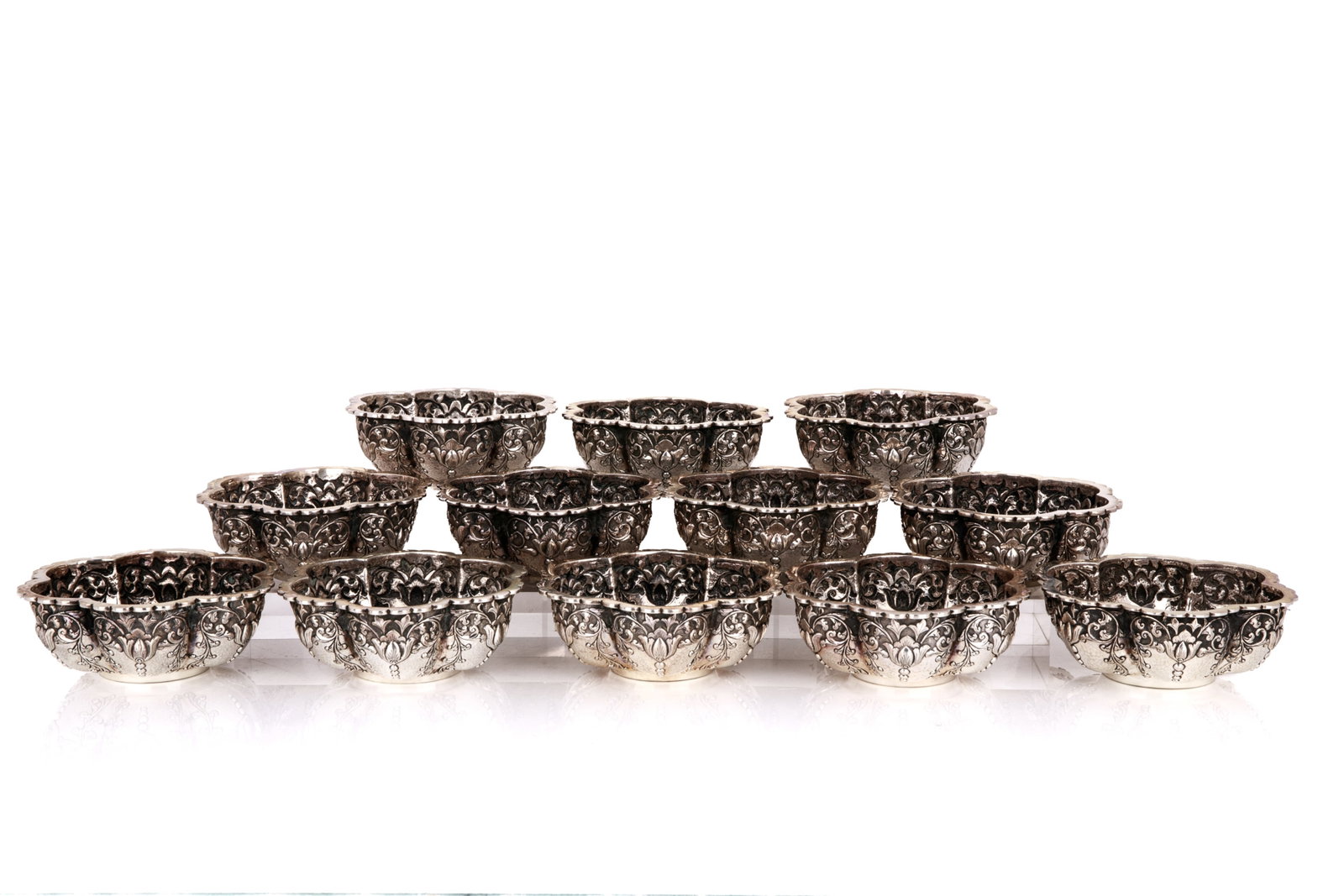 GROUP OF TWELVE SILVER FINGER BOWLS, 1506g: Twelve silver finger bowls in a lobed form with scalloped edges and botanical motifs in repousse across the body. Marked '800' with an unidentified stamp to the underside. Unknown origin, late 19th or